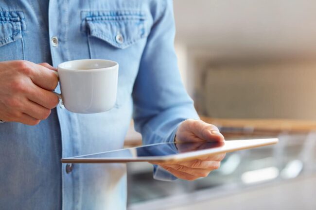 Image of a focused businessman holding a tablet, tracking and monitoring the cash flow of his business, signifying the importance of financial management in achieving business success.