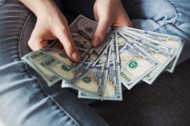 Image of a woman holding an excess amount of cash, symbolizing the concept of too much cash on a company's balance sheet, with the implication that Juna Financial Solutions can assist in achieving the optimal balance for financial health.