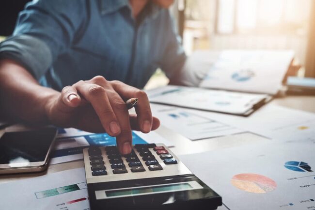 Image of an individual deeply engrossed in studying balance sheets on their computer, provided by Juna Financial Solutions, working towards mastering the key concepts and interpreting financial data to enhance their business's financial health.