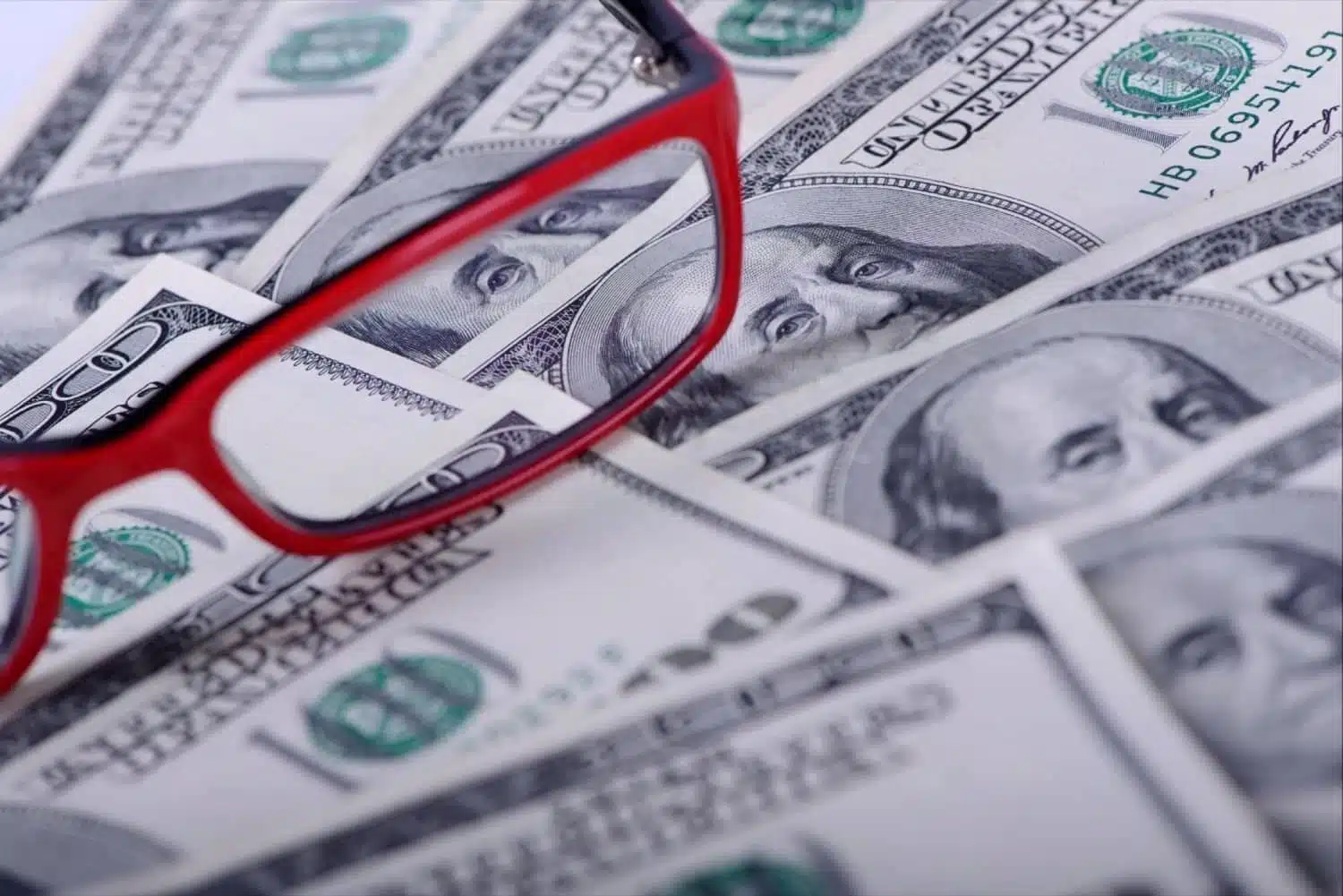 An image of neatly stacked cash next to a pair of eyeglasses, symbolizing the financial challenges entrepreneurs face and the clear insights provided by Juna to navigate them.