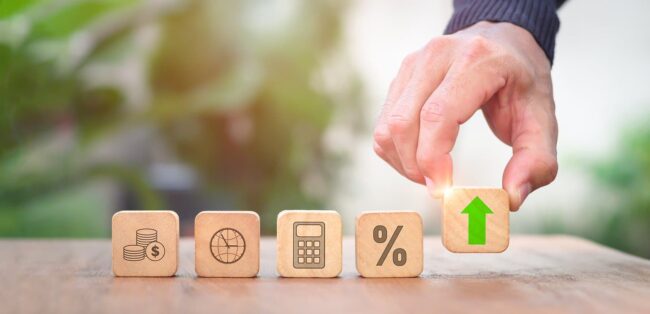 A hand is pointing to wooden blocks with a green arrow on them to signify how you can elevate your business with strategic accounting by Juna.